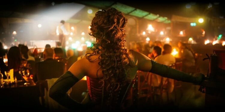 Cabaret performer seen from inside a candlelit Parisian club