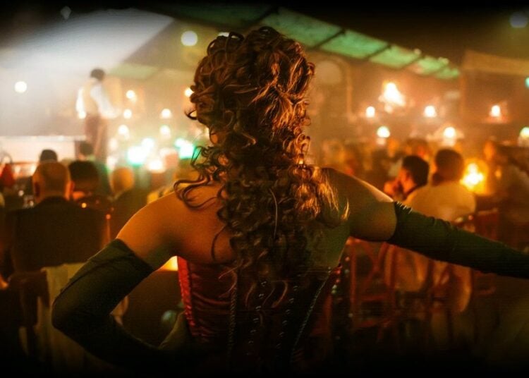 Cabaret performer seen from inside a candlelit Parisian club