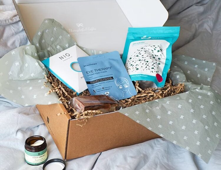 A relaxing gift box arranged on a bed with a magazine and treats