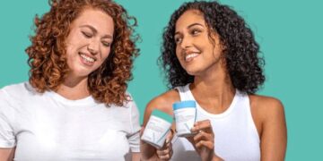 Two women smiling while holding Happy V wellness products