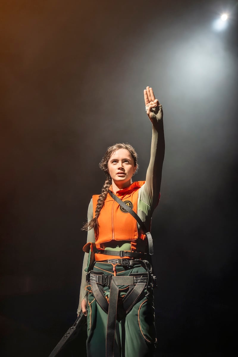 Katniss Everdeen holding the three-finger salute on stage