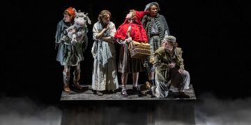 Into the Woods performers on a dark theatrical stage