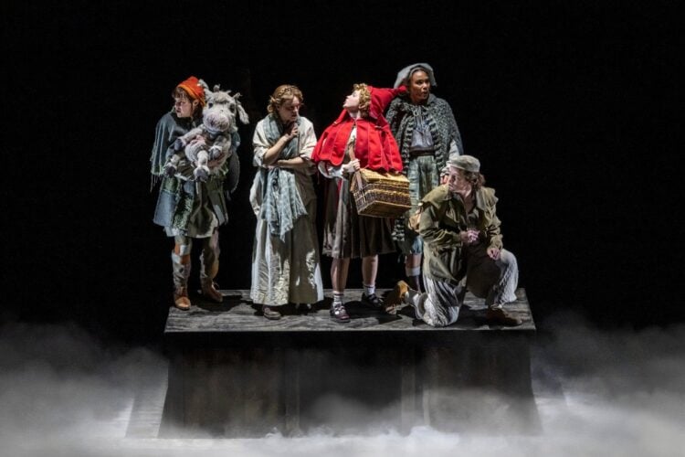 Into the Woods performers on a dark theatrical stage