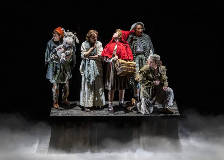 Into the Woods performers on a dark theatrical stage