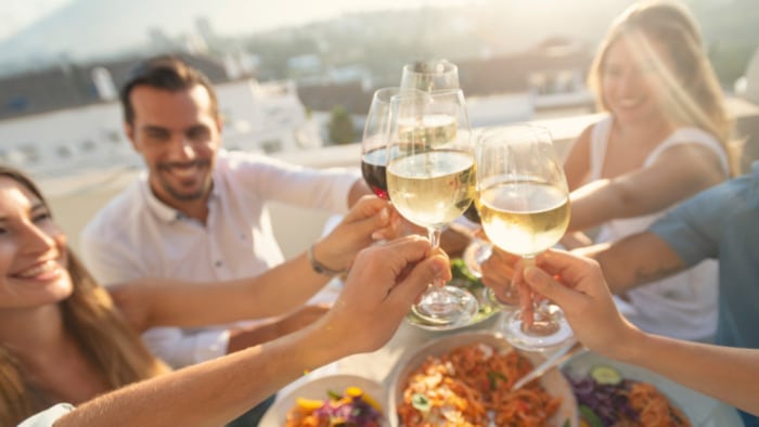 Menschen stoßen bei einem Sommerabend mit Wein an