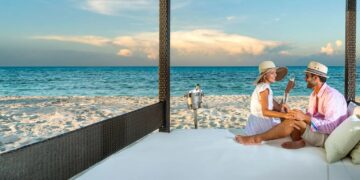 Coppia rilassata su un lettino sulla spiaggia di un resort Ocean