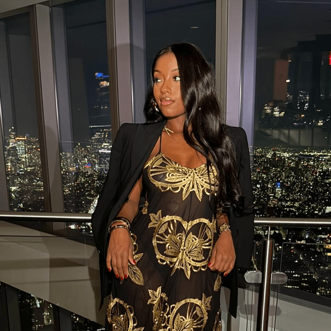 Guest posing inside One World Observatory with New York lights behind her