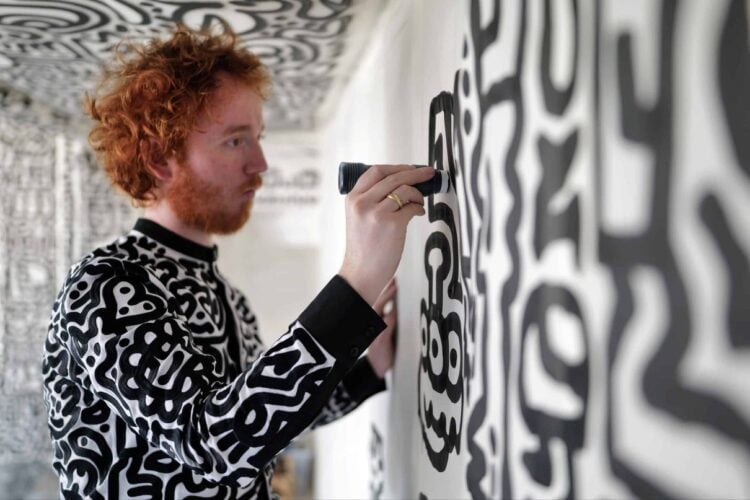 Artist painting a black and white patterned wall at The View from The Shard
