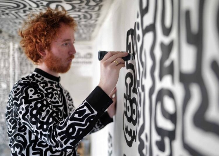 Artist painting a black and white patterned wall at The View from The Shard
