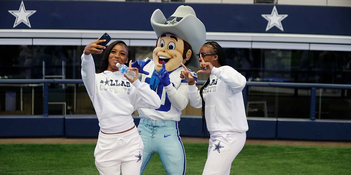 Fans taking a selfie with a Dallas Cowboys mascot inside AT&T Stadium