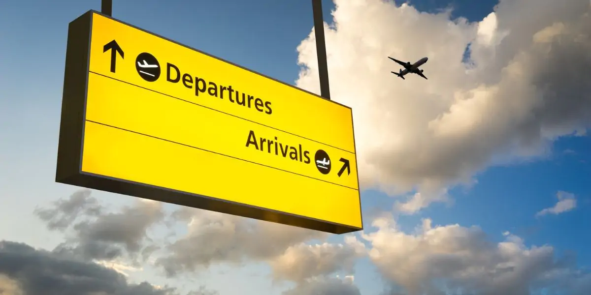 Airport departures board against a blue sky
