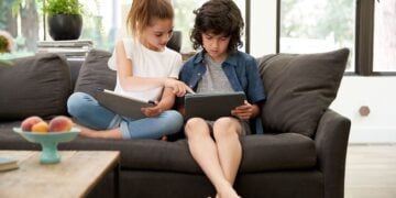 Children using connected devices on a sofa