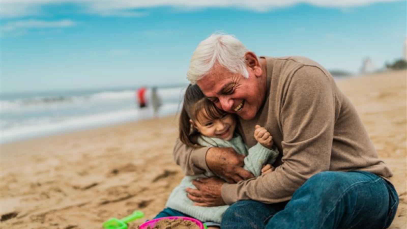 Grandfather hugging a child on a beach