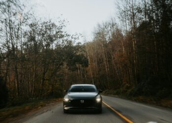 Schwarzes Auto fährt auf einer Waldstraße