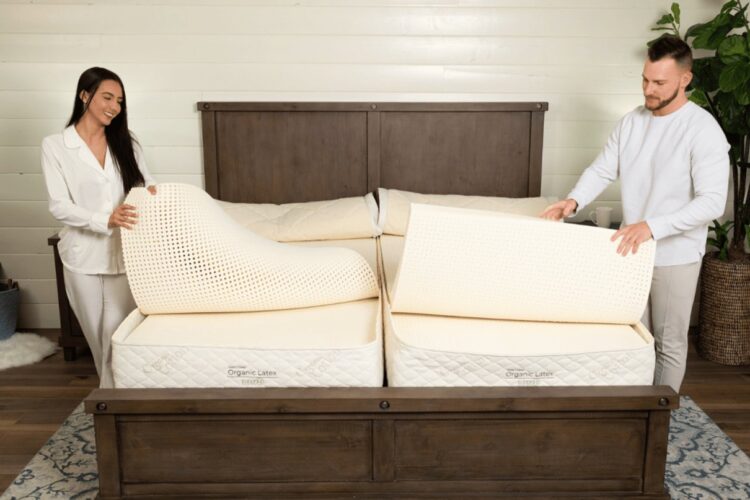 A couple adjusting a Sleep EZ latex mattress in a bright bedroom