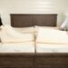 A couple adjusting a Sleep EZ latex mattress in a bright bedroom