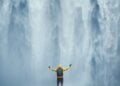 Traveller standing beneath a waterfall