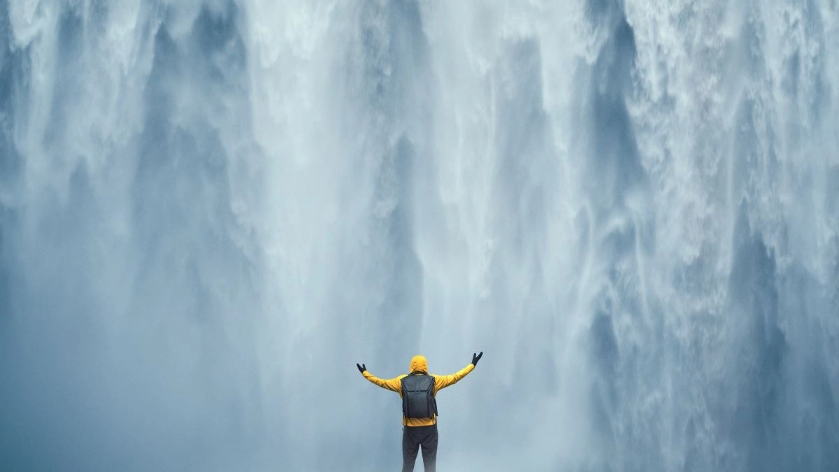 Traveler standing beneath a waterfall