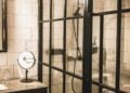 Hotel bathroom with a black-framed glass shower enclosure and white tiled walls