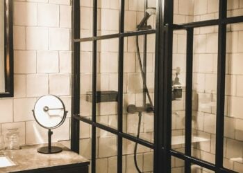 Hotel bathroom with a black-framed glass shower enclosure and white tiled walls