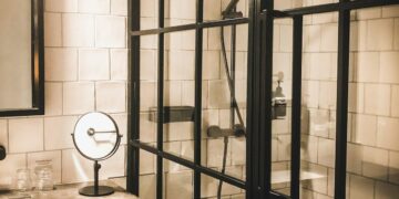 Hotel bathroom with a black-framed glass shower enclosure and white tiled walls