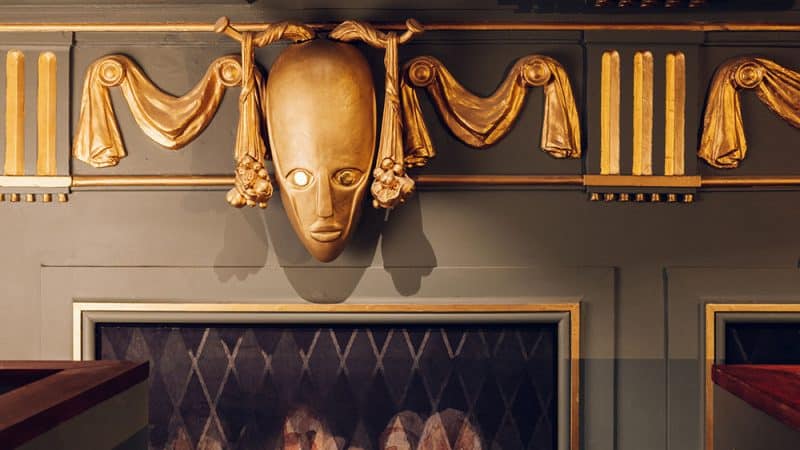 Gold mask wall decoration inside the Kit Kat Club