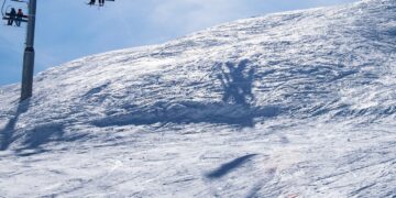 Skiers riding chairlifts above a snowy mountain