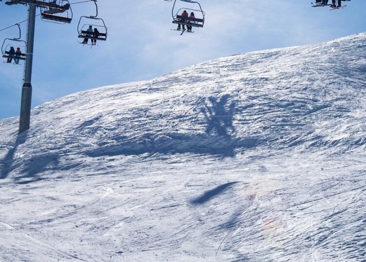 Skiers riding chairlifts above a snowy mountain