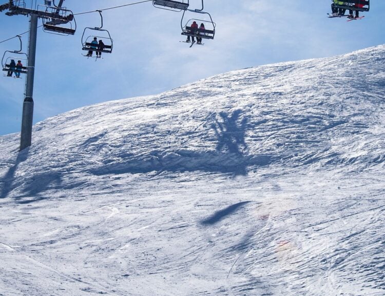 Skiers riding chairlifts above a snowy mountain
