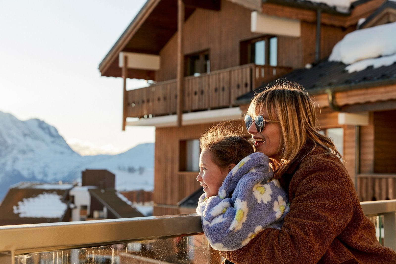 Family looking out over a snowy mountain resort from a balcony