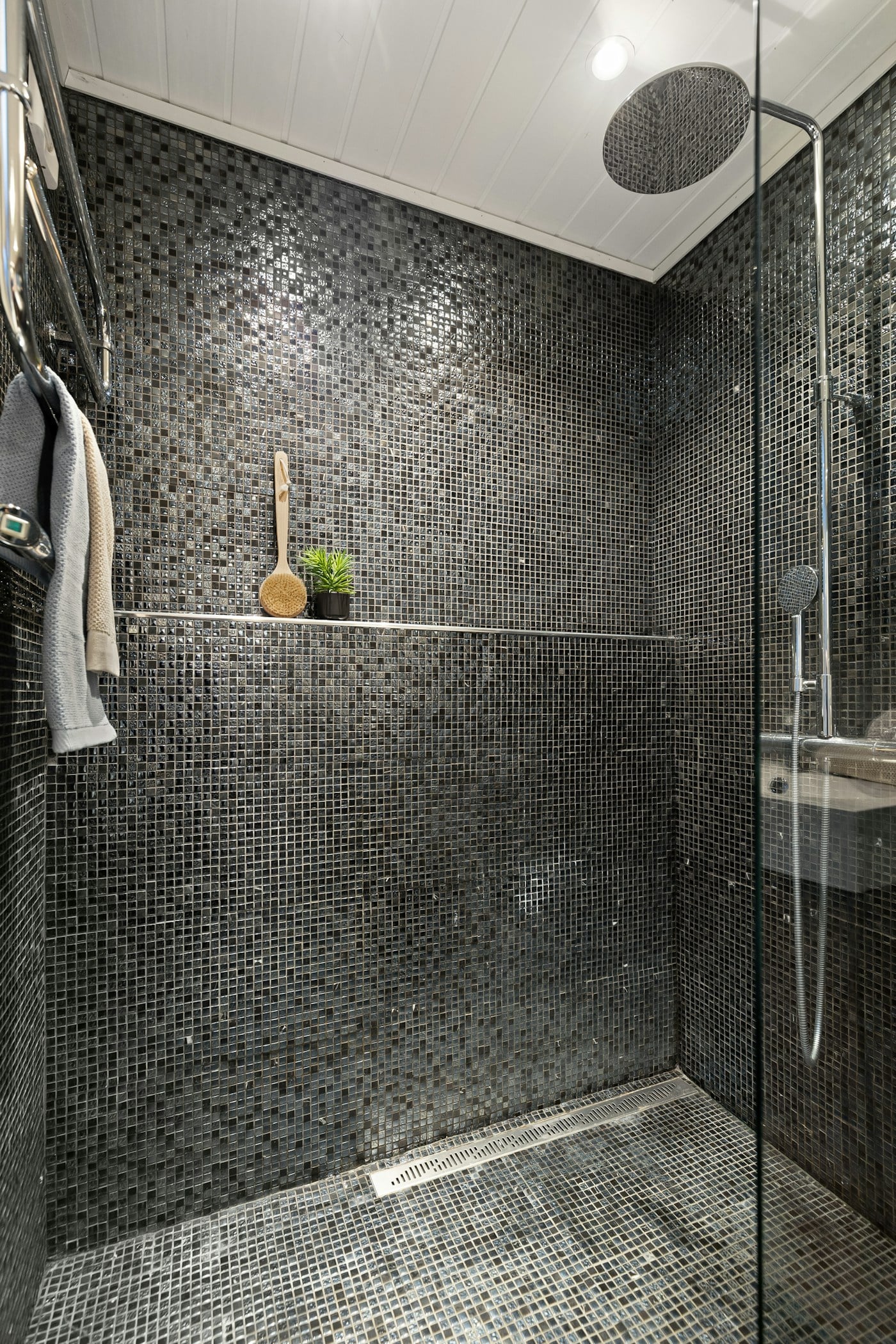 Dark tiled walk-in shower with chrome fixtures