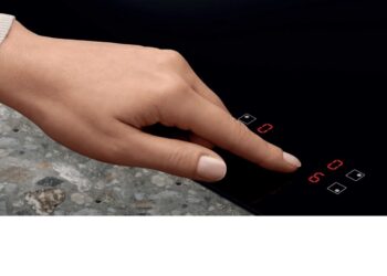 Una mano usa i comandi touch del piano a induzione Electrolux