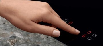 Una mano usa i comandi touch del piano a induzione Electrolux