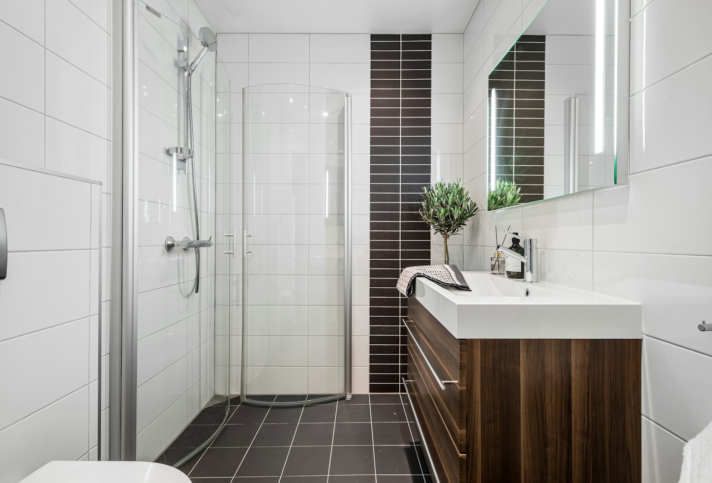 White tiled bathroom with corner glass shower and wooden vanity