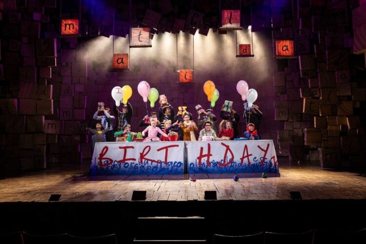 Cast performing together in a Matilda stage scene
