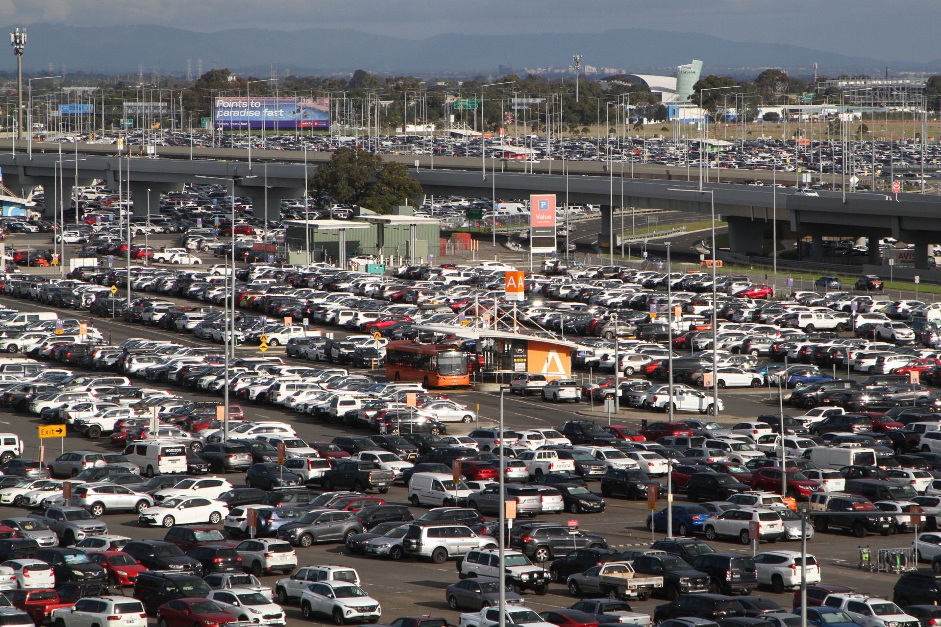 Airport shuttle bus waiting among cars in a value car park