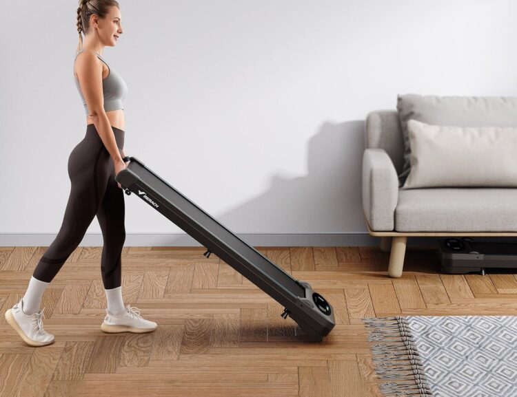 A woman carries a Merach T26B1 treadmill through a bright living room