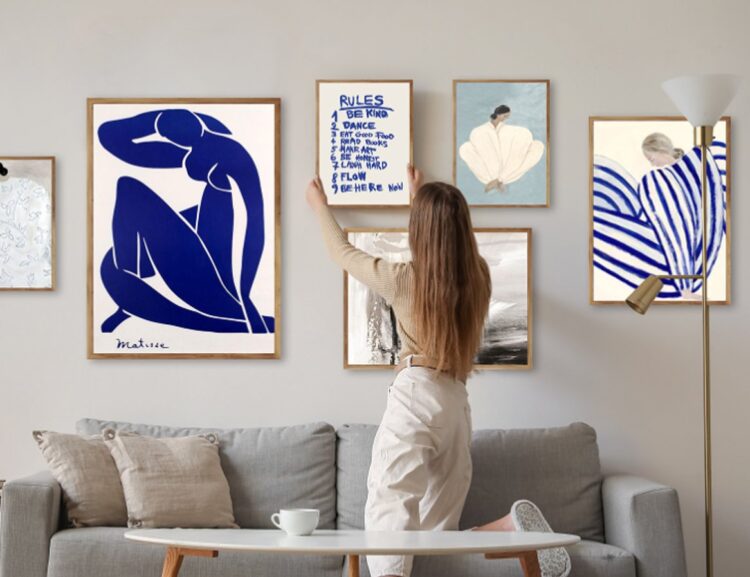 A person arranging framed art above a sofa in a living room