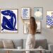A person arranging framed art above a sofa in a living room