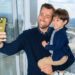 A parent and child take a selfie beside the windows overlooking London