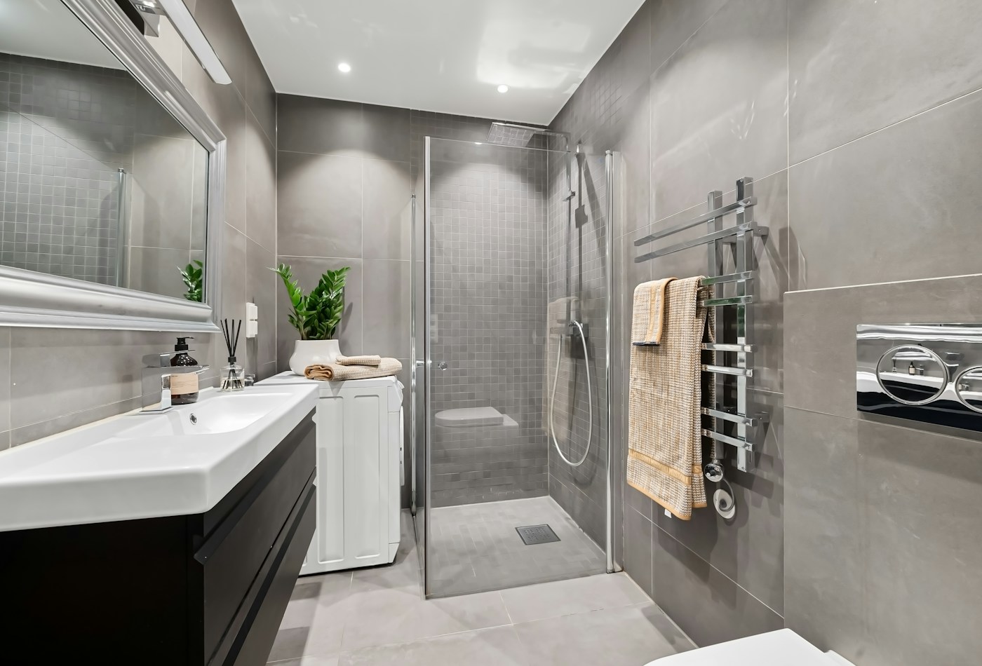 Grey tiled bathroom with frameless glass shower and white vanity